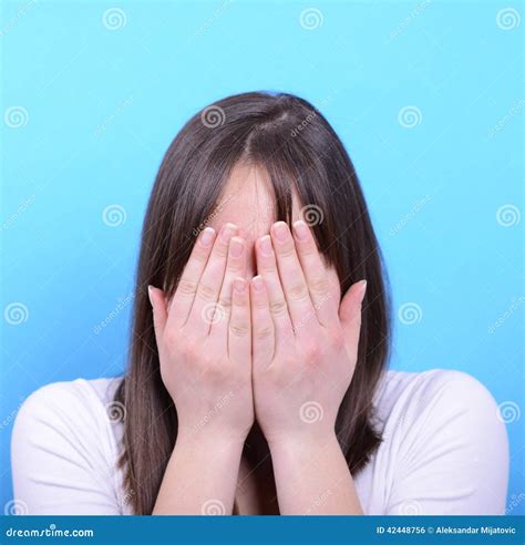 Portrait Of Covering Her Face With Hands Against Blue Background Stock