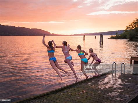 Girls Jumping Into Lake From Wooden Dock Photo Getty Images