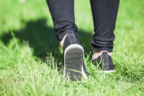 foot walk with step out on green grass at sunny day rear view at female legs with shoes and