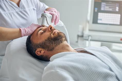 Doctor Beautician Treating Male Skin With Laser Device Stock Photo