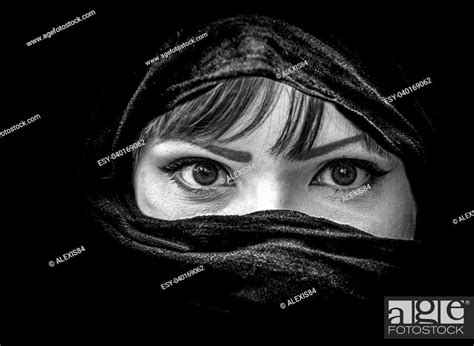 portrait of beautiful arab woman with brown eyes wearing black scarf in black and white stock