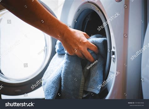 Hand Puts Laundry Into Washing Machine Stock Photo 1019057059