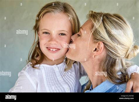 Portrait Of Smiling Little Girl Kissed By Her Mother Stock Photo Alamy