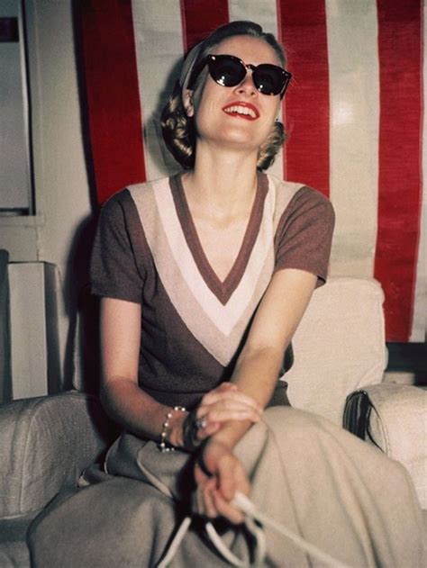 A Woman In Sunglasses Sitting On A Chair With A Handbag And An American