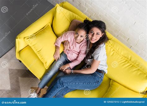 Top View Of Mother And Daughter Sitting On Couch Together And Looking Stock Image Image Of