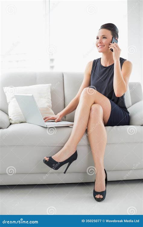 Beautiful Well Dressed Woman Using Laptop And Cellphone On Sofa Stock
