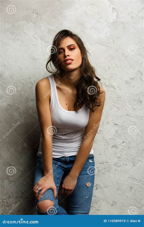 Photo Of Beautiful Brunette In White Tank Top And Ripped Jeans Stock