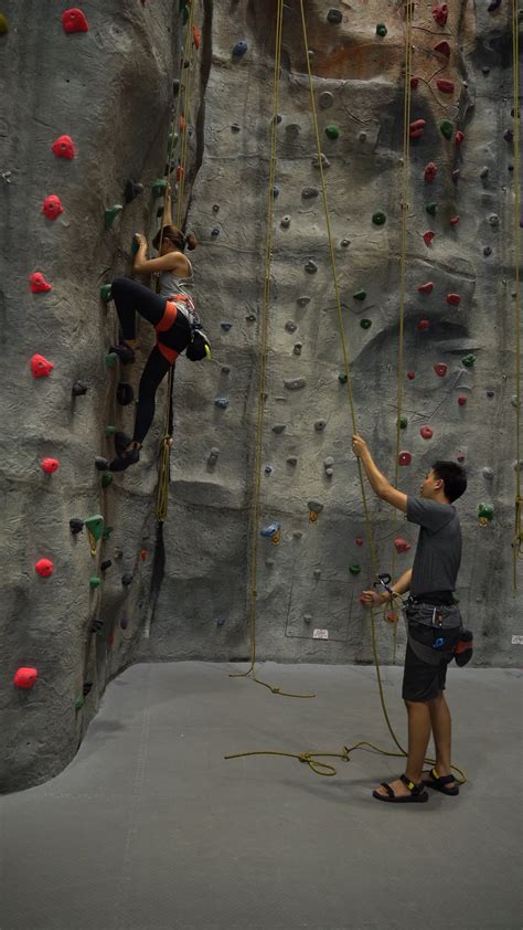A Woman Climbing Up The Wall While A Man Standing On The Ground · Free