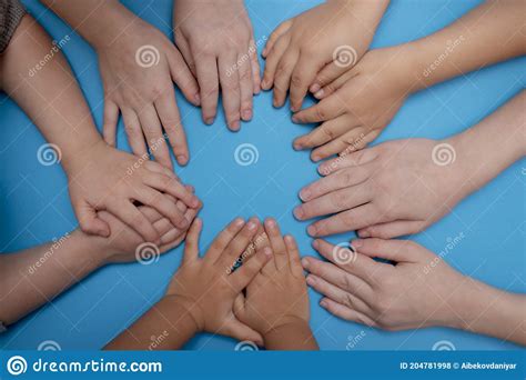 Group Of Children Putting Their Hands Together On Blue Paper Stock