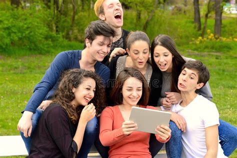 Grupo De Adultos Jovenes Que Hojean Una Tableta Afuera Foto De Archivo