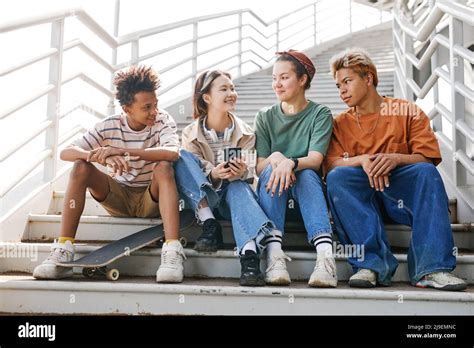 Full Length Portrait Of Diverse Group Of Teenagers Sitting On Metal