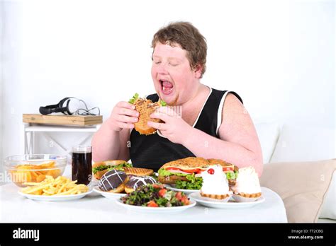 Fat Man Eating A Lot Of Unhealthy Food On Home Interior Background