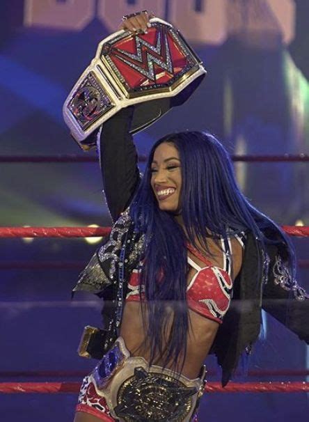 A Woman In A Wrestling Ring Holding Up A Trophy And Smiling At The