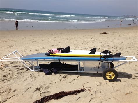 A Surfboard Is Sitting On The Beach Next To A Cart