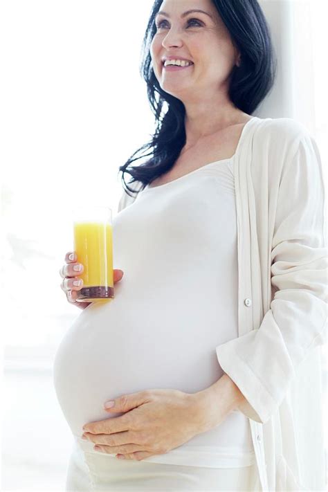 pregnant woman touching tummy with juice photograph by ian hooton science photo library fine