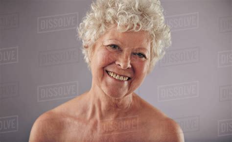 Portrait Of Beautiful Naked Senior Woman Looking Happy Against Grey E26