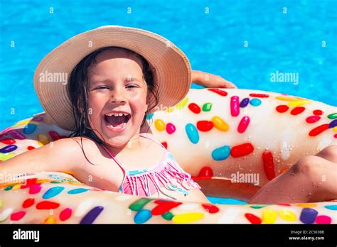 ein kleines schönes mädchen in einem hut ist das baden in einem auf aufblasbaren rin im pool