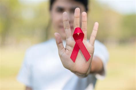 Premium Photo Hand Holding Red Ribbon For Supporting People Living And Illness Healthcare And