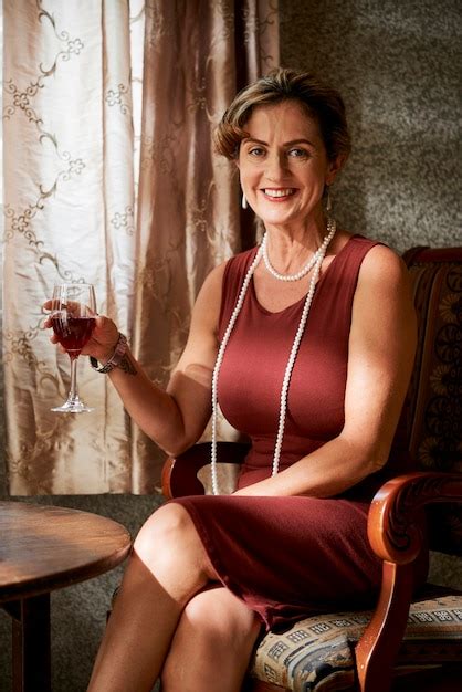 premium photo portrait of happy elegant mature woman with pearl necklace enjoying glass of red