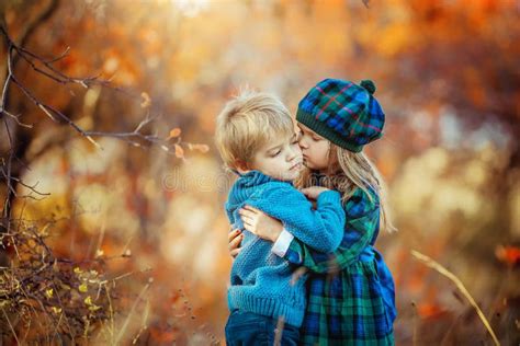 Children Dressed In Warm Autumn Clothes Hug And Smile In The Red And