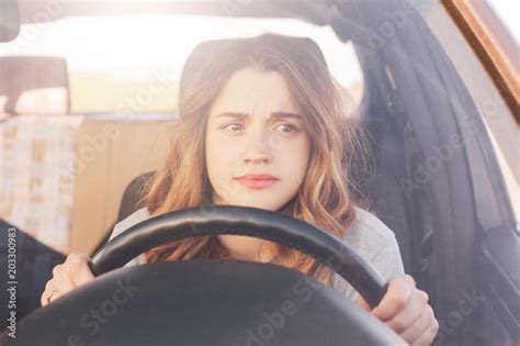 Nervous Female Driver Sits At Wheel Has Worried Expression As Afraids