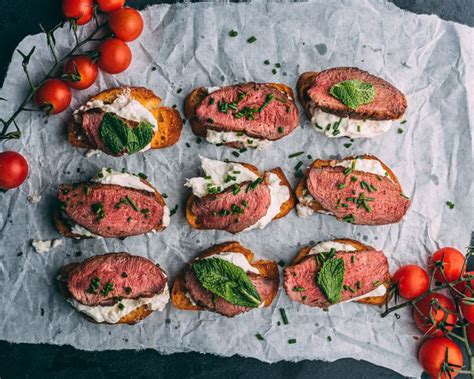 Small Sandwiches With Meat Cheese And Fresh Herbs On Paper Next To