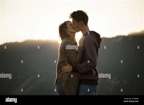 romantische junge paar küssen leidenschaftlich bei sonnenuntergang berge im hintergrund