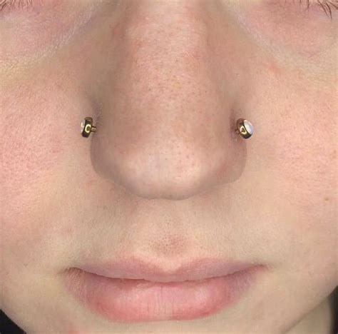 A Womans Nose With Two Piercings On Top Of Her Nose And One Behind Her