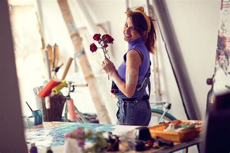 A Young Female Artist With Flowers Is Posing For A Photo In Her Studio