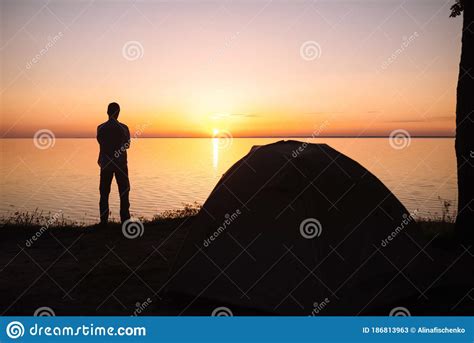 A Man Stands Facing The Sun By The Sea And Meets The Sunrise Stock