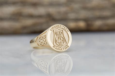 A Gold Signet Ring With An Emblem On The Front And Side Sitting On A
