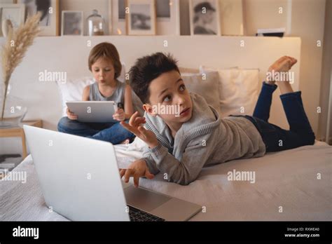 Two Children Boys In Parents Bed At Morning With Laptop And Tablet