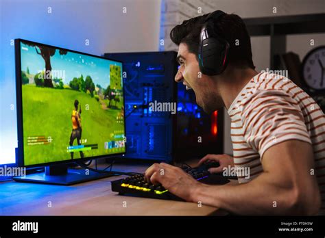Portrait Of Caucasian Gamer Guy Yelling While Playing Video Games On Computer Wearing Headphones
