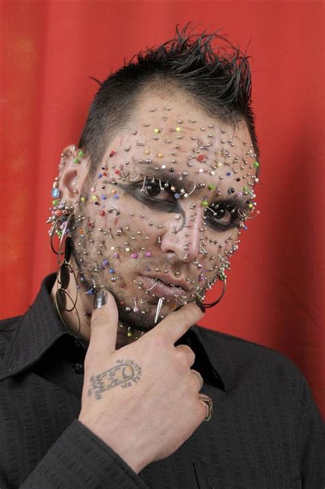 a man with his face covered in confetti and piercings poses for the camera