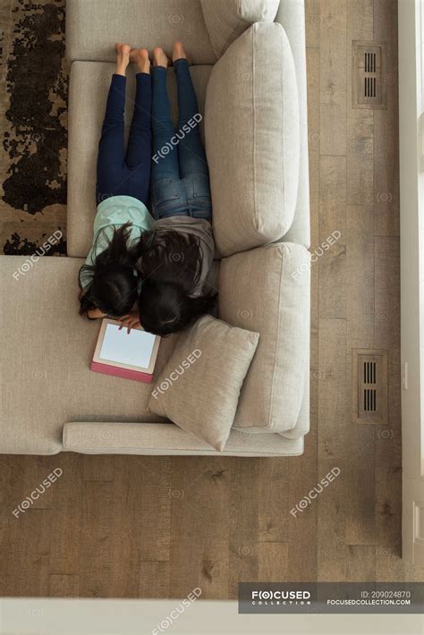 Siblings Using Digital Tablet In Living Room At Home — Casual Clothing Asian Ethnicity Stock