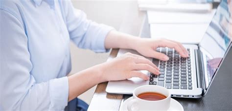 Business Concept Woman In Blue Shirt Typing On Computer With Coffee On Office Table