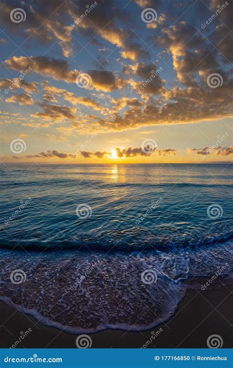 Beautiful Sunrise Cloudscape Over The Sea With Waves Lapping The Beach