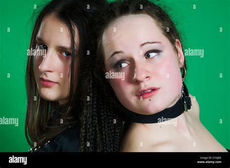 Two Lesbian Sexy Gothic Women With Dreads Wearing Bdsm Outfit On Green Background Stock Photo