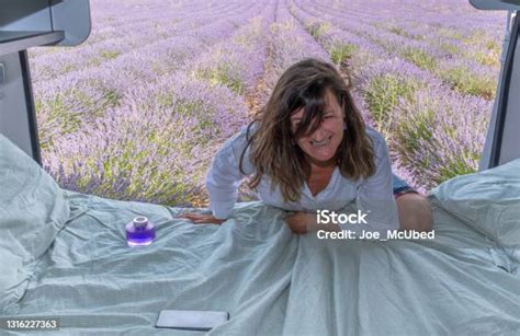 Camper In Lavender Field Woman Laughing As She Climbs Into Bed Stock