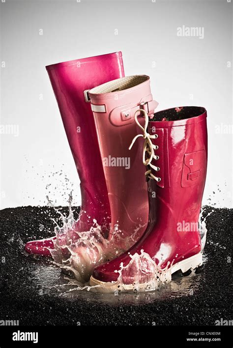 Three Pink Rubber Boots Splashing In A Puddle Stock Photo Alamy