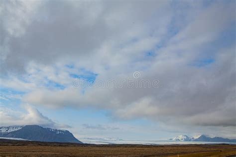A Distant Snow Mountain In Iceland With Changing Clouds Floating In The
