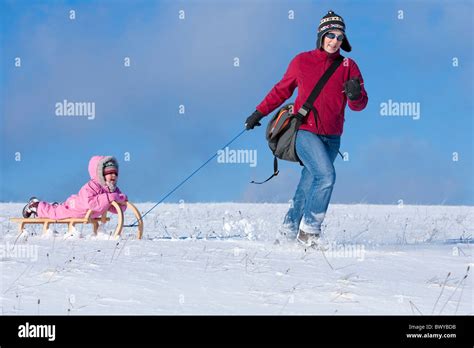 Woman Pulling Infant Girl On Wooden Sled In Winter Landscape Dobel