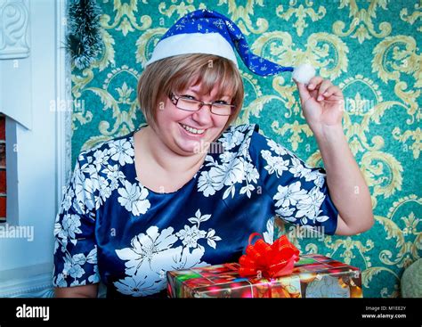 Girl In Santa Hat Sitting Near The Fireplace At Home And Keeps The T