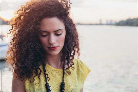 Portrait Of Beautiful Woman With Curly Hair By River By Stocksy