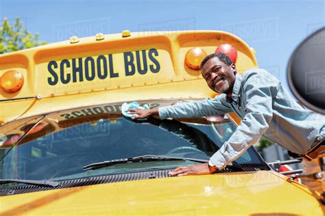 Smiling Mature African American Bus Driver Wiping Front Window Of