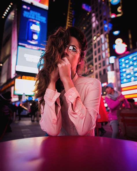 A Woman Sitting At A Table Talking On Her Cell Phone In Times Square