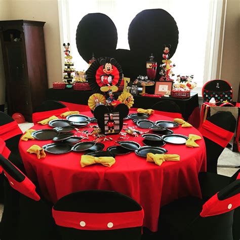 A Mickey Mouse Themed Birthday Party With Red And Black Table Cloths Plates And Decorations