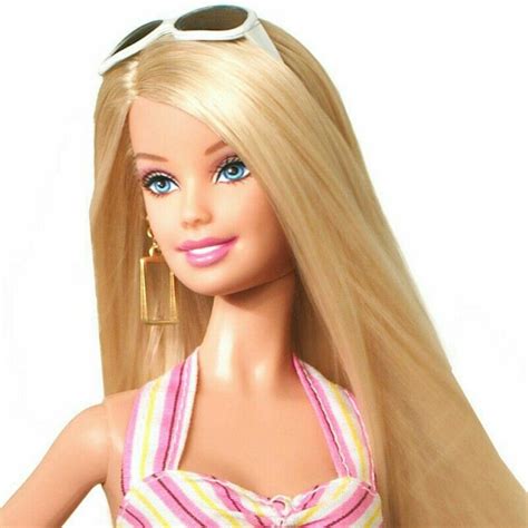 A Barbie Doll With Long Blonde Hair Wearing Sunglasses And A Pink Striped Dress Is Standing In