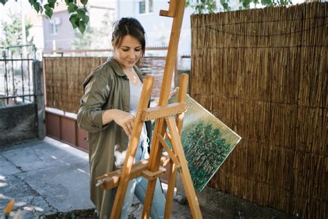 Female Artist Standing In Yard While Holding Painted Canvas Stock Image