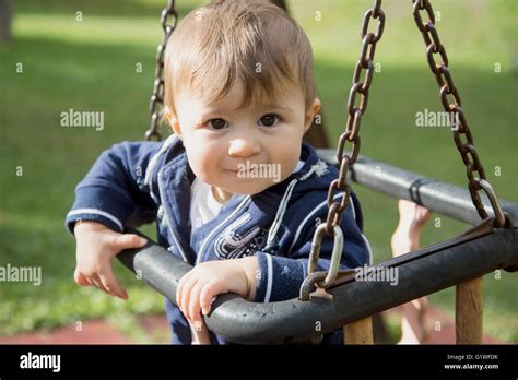Portrait Of Lovely One Year Old Baby Girl Sitting On Swings At